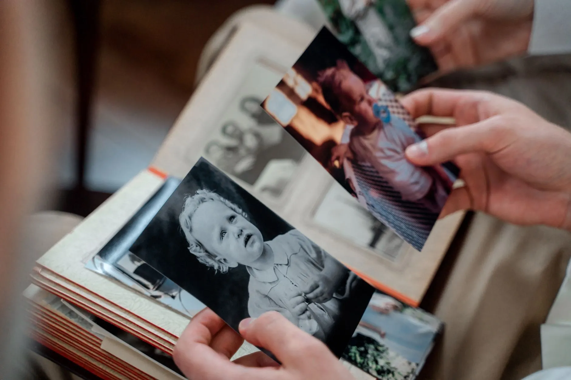 A pair of hands holding a small damaged black and white photograph